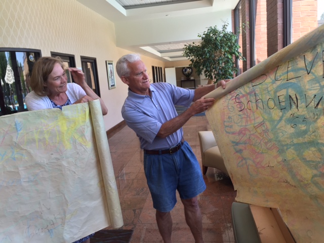 Carol Pinkos Fotopolous and Jim Barton inspect a large sheet of newsprint signed by all the class of 1965.  Come and see at the reunion!